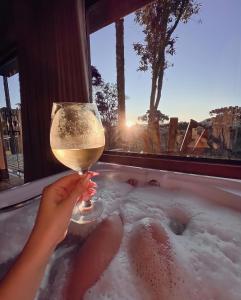 乌鲁比西Sunset Serrano Chalés的浴缸里拿着葡萄酒的人