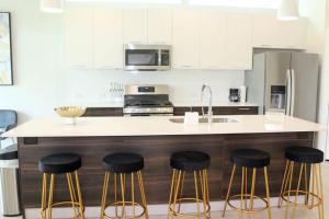 休斯顿Modern Minimalist Luxury Retreat的厨房配有带凳子和水槽的台面