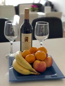 格莱内尔格Glenelg resort style beachside apartment的水果盘,包括一瓶葡萄酒和两杯