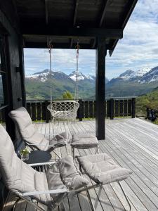 斯特兰达Strandafjellet Panorama Lodge - Large Cabin with Majestic Mountain View的门廊配有椅子和秋千,享有山景。