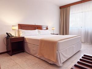 圣玛丽亚Hotel Central Santa Maria的一间卧室配有一张大床和一部电话