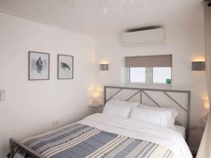 KentOcean View apartment, beautiful sea views的白色卧室配有一张床,墙上挂有两张照片