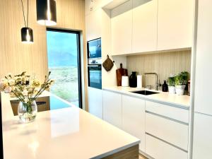 KleppstadNew luxury cabin near Henningsvær Lofoten的厨房配有白色橱柜和花瓶,位于柜台上