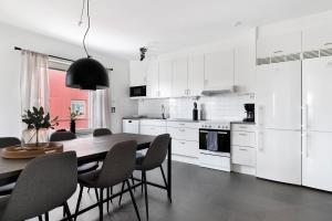 皮特奥Guestly Homes - 3BR Modern Apartment的白色的厨房配有木桌和椅子