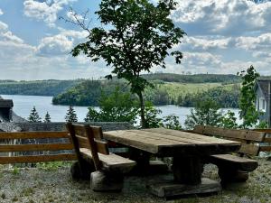 施莱茨Auszeit im Wald direkt am See的一张木餐桌,配有两个长椅和一个湖泊