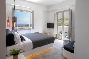 皮尔戈斯Maeva Suites Santorini的一间白色卧室,配有床和2个窗户