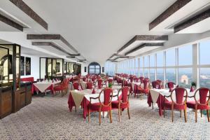 新德里新德里艾美酒店 的用餐室设有桌子和红色椅子以及窗户。