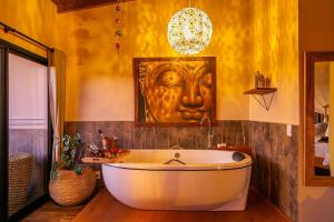 普腊亚罗萨Shiva Boutique Hotel - Praia do Rosa的带浴缸的浴室,墙上设有面部
