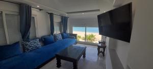 弗尼迪克Résidence Al Amine Plage accès direct à la plage的客厅配有蓝色的沙发和平面电视。