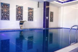 巴士拉Move npic Zenat al Hayat Hotel的一个带蓝色瓷砖和窗户的游泳池