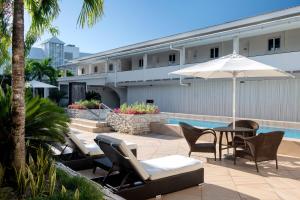 阿皮亚萨摩亚阿吉格雷简易别墅喜来登酒店的游泳池旁的天井配有椅子和遮阳伞。