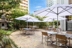 东京东京喜来登米亚科酒店的一个带桌椅和遮阳伞的庭院。
