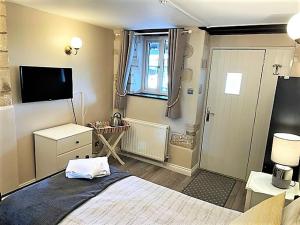 水上伯顿Cotswold Merrymouth Inn的一间卧室配有一张大床和电视