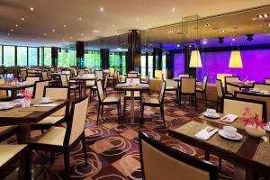 莱比锡莱比锡威斯汀酒店的餐厅配有桌椅和紫色照明