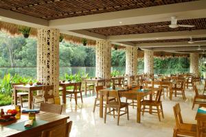 乌布巴厘岛乌布斯塔拉翠贡精选酒店的餐厅设有木桌、椅子和窗户。