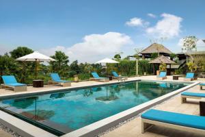 乌布巴厘岛乌布斯塔拉翠贡精选酒店的度假村的游泳池,配有蓝色的椅子和遮阳伞