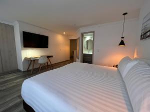 波哥大Suites 109 GH Usaquén的酒店客房设有一张白色大床和一张书桌
