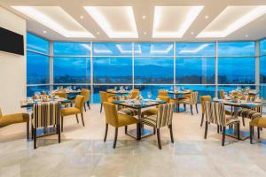 昆卡昆卡福朋喜来登酒店的餐厅设有桌椅和大窗户。