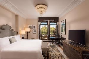 塞维利亚Hotel Alfonso XIII, a Luxury Collection Hotel, Seville的一间卧室配有一张床、一台电视和一架钢琴