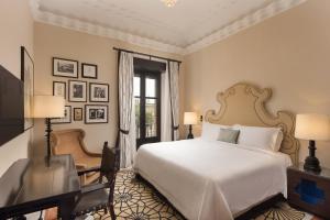 塞维利亚Hotel Alfonso XIII, a Luxury Collection Hotel, Seville的一间卧室配有一张床、一张书桌和一个窗户。