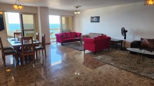 亚历山大Alex sea view apartment - families only的客厅配有红色的沙发、桌子和椅子