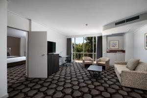 堪培拉Rydges Canberra的酒店客房设有床和客厅。