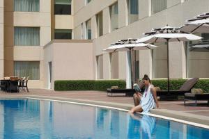 浦那Four Points by Sheraton Hotel and Serviced Apartments Pune的坐在游泳池旁的男人和女人