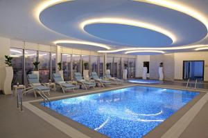 麦地那Marriott Executive Apartments Madinah的酒店大堂设有大型游泳池和椅子
