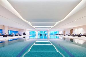 滁州滁州港汇喜来登酒店的一座游泳池,位于一座带椅子和水的建筑中
