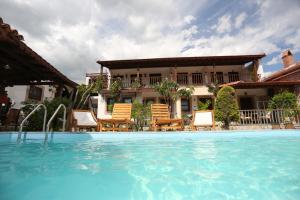 贝尔加马阿克罗波利斯酒店的一个带椅子的游泳池和一个背景房子