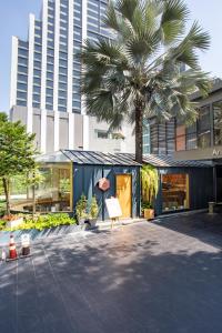 曼谷阿里斯顿酒店曼谷的一座建筑前的棕榈树