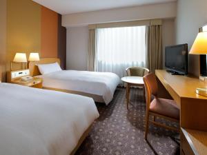 京都Miyako Hotel Kyoto Hachijo的酒店客房设有两张床和电视。