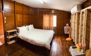 佛丕Banthai Guesthouse的卧室配有白色的床和木墙