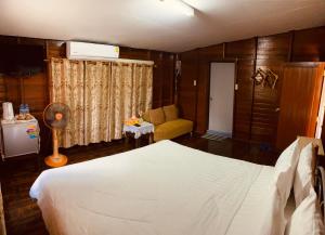 佛丕Banthai Guesthouse的卧室配有白色的床和沙发