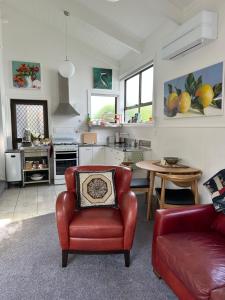 奥克兰The Partchery Devonport的一间带红色椅子的客厅和一间厨房