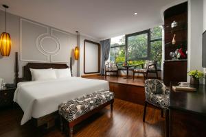 河内Salute Premium Hotel & Spa的一间卧室配有一张床、一张桌子和一把椅子