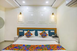 阿拉哈巴德FabHotel Cosmos的一间卧室配有一张带色彩缤纷枕头的大床