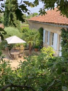 米尼亚卢博瓦尔Chambre d'hôtes à Mignaloux-Beauvoir- le Thil的一个带桌子和遮阳伞的花园以及一座房子