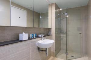 悉尼Meriton Suites Campbell Street, Sydney的一间带水槽和淋浴的浴室