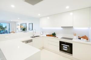 凯阿玛Kiama Waterfront Apartment的白色的厨房配有白色橱柜和水槽