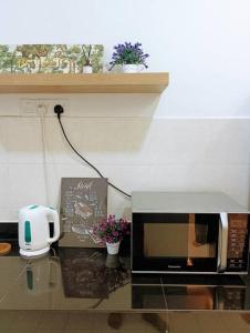 加影Tenang Retreat Holiday Home的厨房柜台配有微波炉和鲜花。
