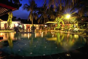 海神庙Dewi Sinta Hotel and Restaurant的夜间在度假村的一个大型游泳池