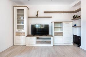 希洪MyHouseSpain - Precioso piso cerca de la playa的一间带电视和白色橱柜的客厅