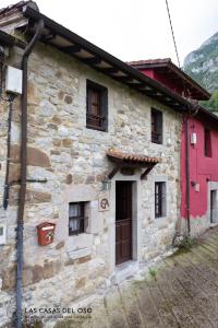 La Seronda de Villaorille - Las Casas del Oso的一座石头房子,设有红色的门和窗户