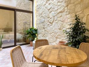 科尔多瓦Arcos de Medina - Apartamentos premium的石墙房间内的一张木桌和椅子