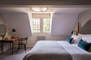 福伊Fowey Hall Hotel的一间卧室配有一张床、一张书桌和一个窗户。
