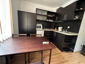 圣弗拉斯Siana 4 Apartment (15)的一间带木桌的厨房和一间带黑色橱柜的厨房