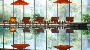 武汉武汉光明万丽酒店的一座大楼内带椅子和遮阳伞的游泳池