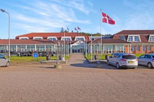 格林哥里皮奈霍斯酒店的停车场内有挂有吊旗的汽车的建筑物