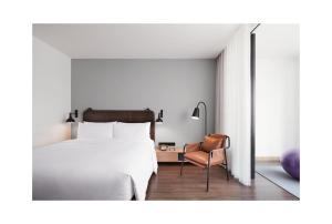深圳深圳北站Moxy酒店的卧室配有白色的床和椅子